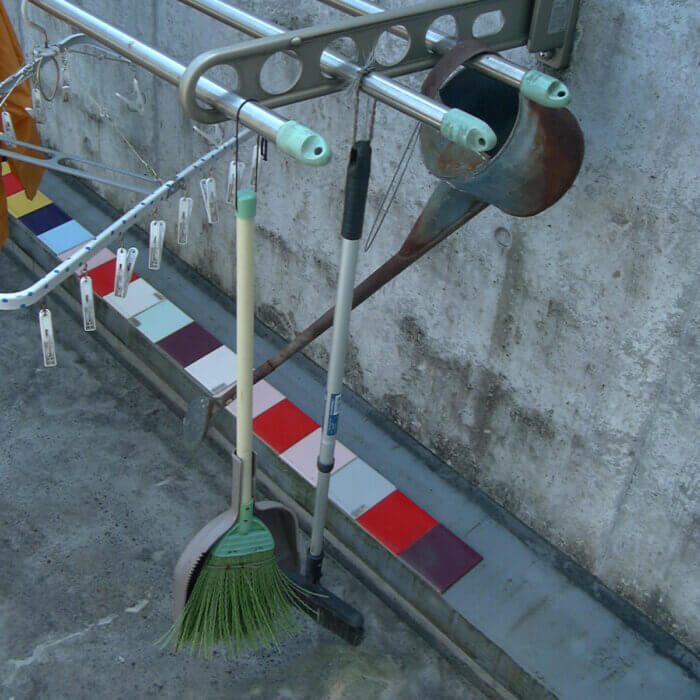 掃除したあと掛けて片付けられるように、物干し竿にフックでほうきなどの掃除用具を取り付けています