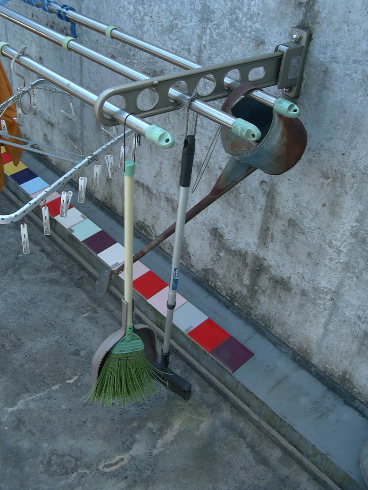 掃除したあと掛けて片付けられるように、物干し竿にフックでほうきなどの掃除用具を取り付けています