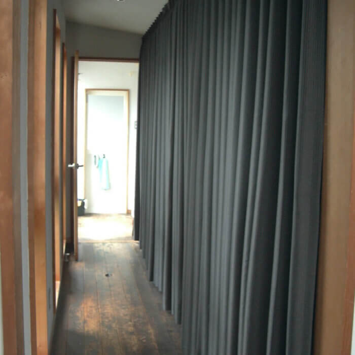 二階廊下のカーテンを黒系のタップリヒダの入ったカーテンに変更