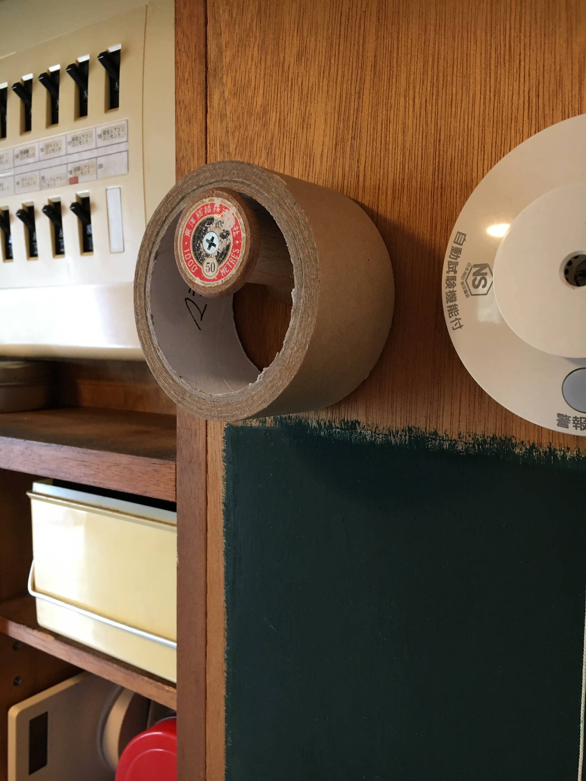 昔の木製糸巻きをキッチンの壁に取り付け、ガムテープを引っ掛けられるフックにしました