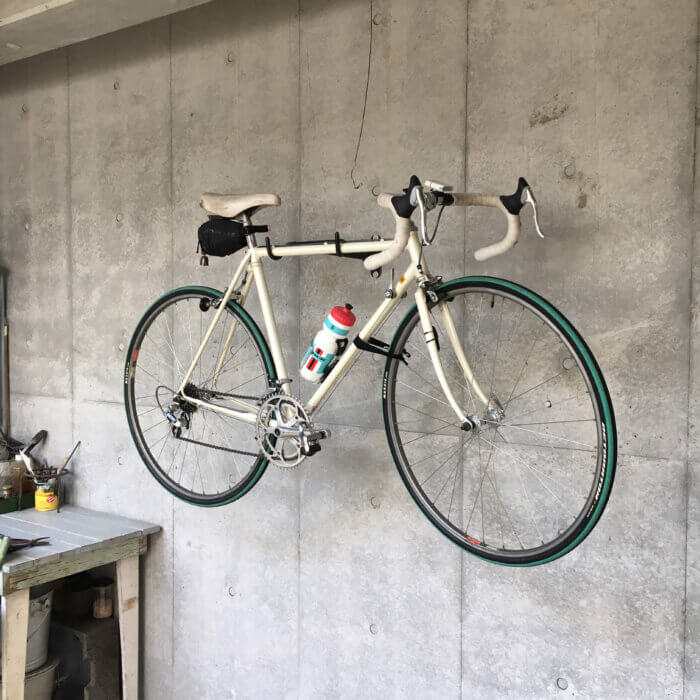 事務所の壁から外の土間に吊られた自転車