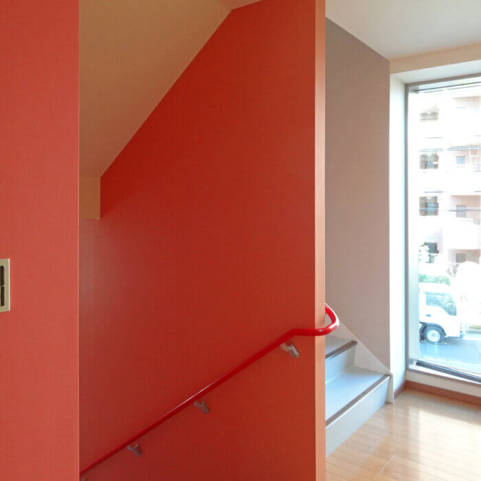 DFビル　内装デザイン　オレンジの壁紙と赤い手すりがある階段