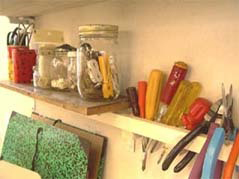 壁に掛けられた工具と、小さな棚に置かれた細かいものが入った瓶と缶