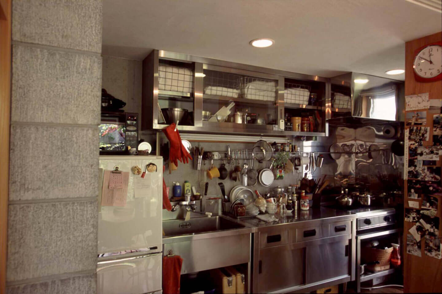 プロ仕様の厨房用品のリサイクル店で少しずつ集めた調理器具がたくさん収納されている、コンクリートとステンレスのキッチン