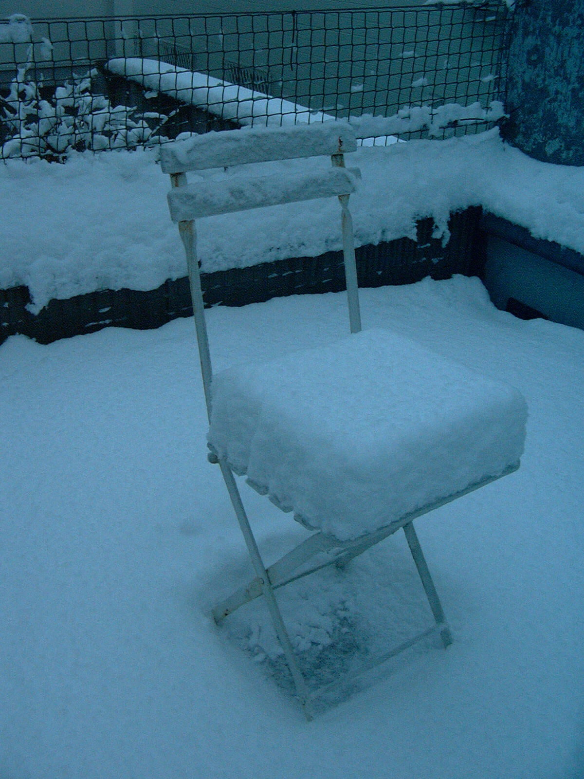 積もった雪が厚いクッションのように見える、雪が積もった庭に置いてある椅子
