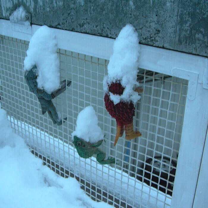 ベランダのネットにかけられた3体の怪獣の人形に、雪が積もっている