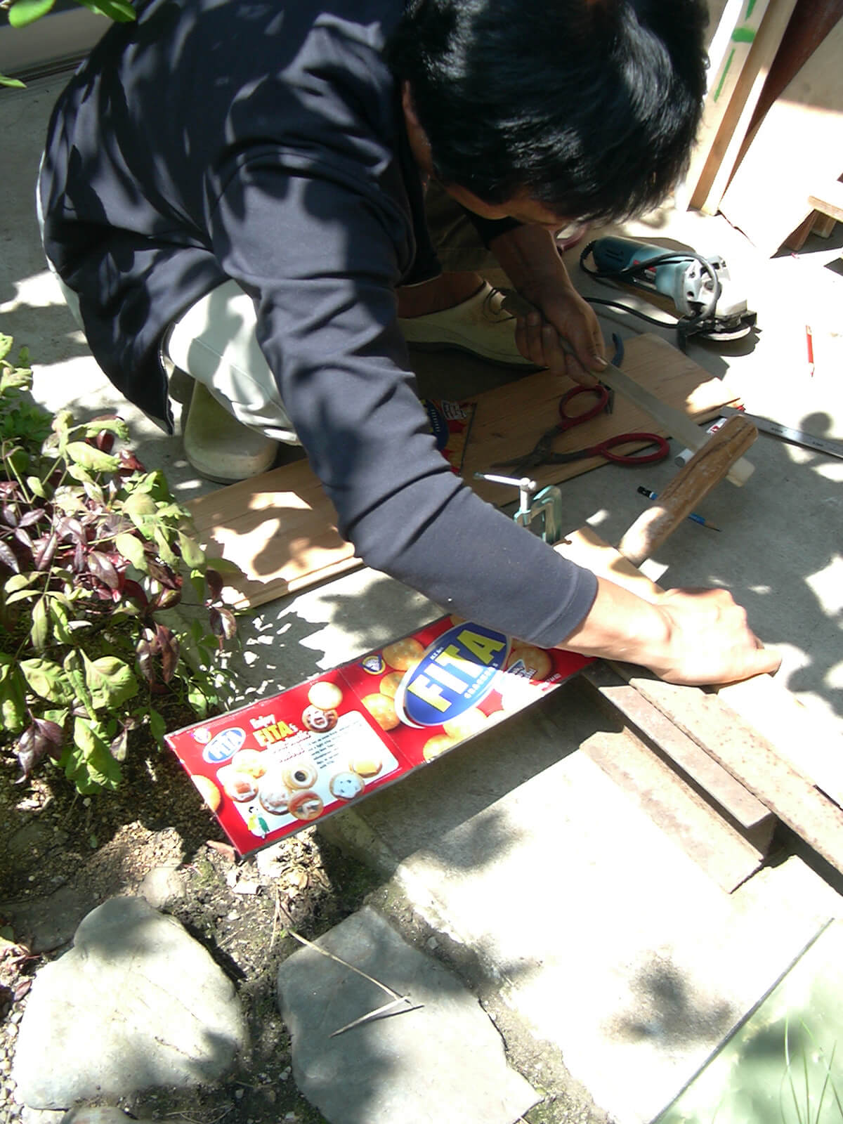 庭で、ポストを作るための木材の寸法を測る男性