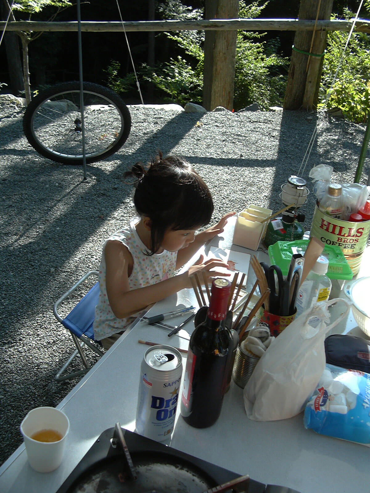 夏のキャンプの屋外で、テーブルに座り絵を描いている女の子