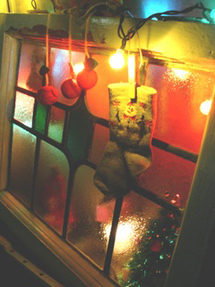 子供が飾ったクリスマススペース。ステンドグラスの窓枠に吊るした靴下とボールのオーナメントと、その後ろに見える、小さなクリスマスツリーとライト