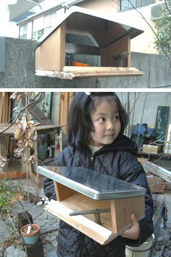 庭で手作りの小鳥の餌台を持っている女の子