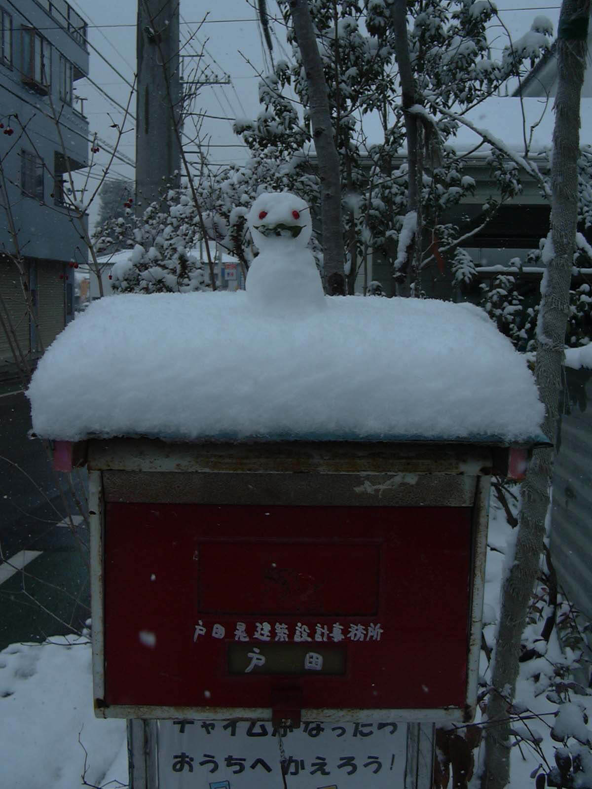 雪の日に、自宅のポスト上に置かれた小さな雪だるま
