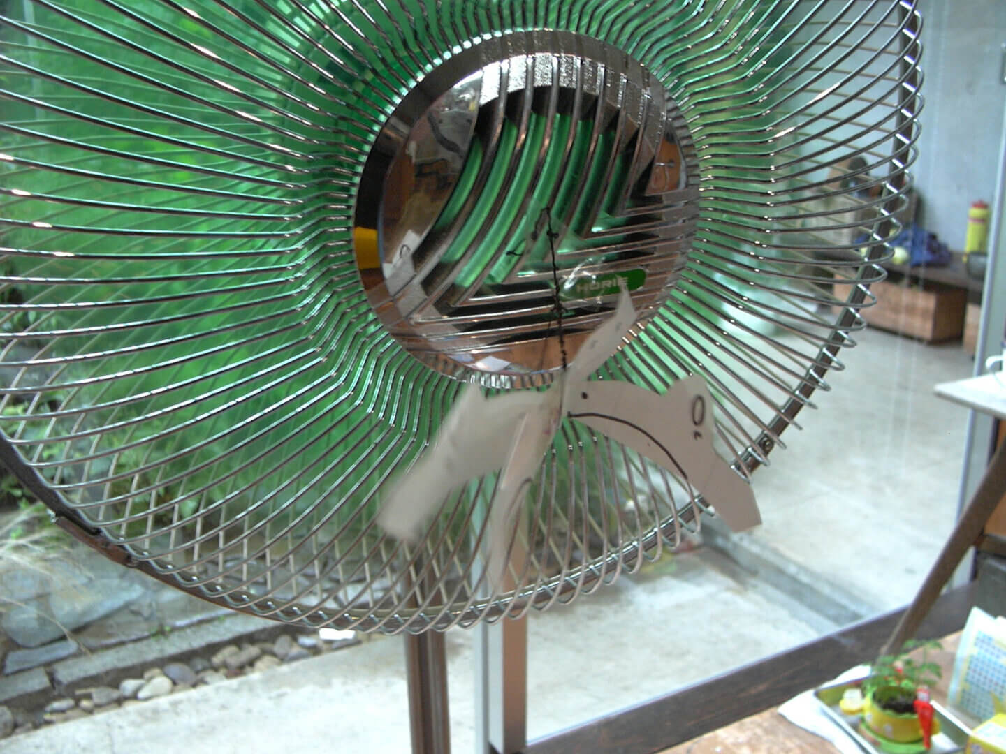 扇風機の中心につけられた紙のイルカが、扇風機の風で泳ぐように揺れている
