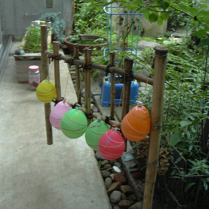 庭の竹の柵に吊るされた、町内会の祭りでゲットしたカラフルな6個の水風船