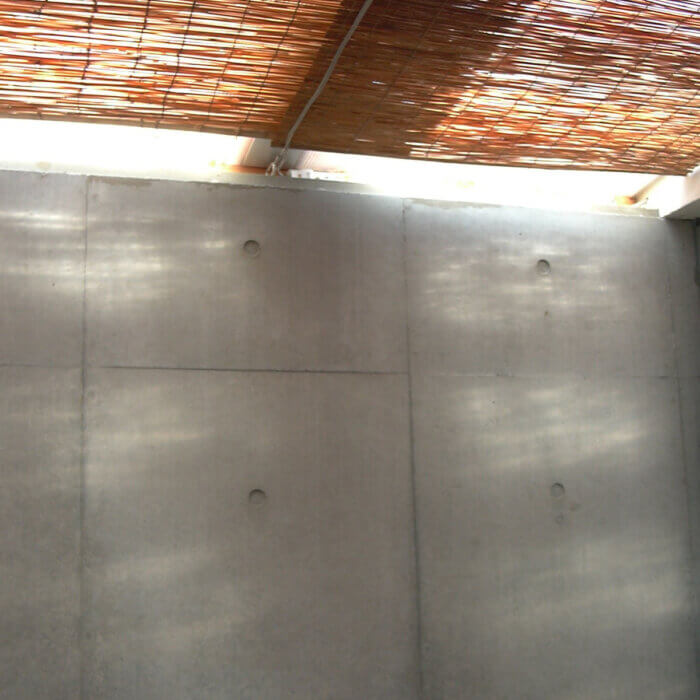 吹き抜けの天井につけられたスダレから夏の日差しが差し込み、コンクリートの壁にゆらゆらと海のような模様が映っている