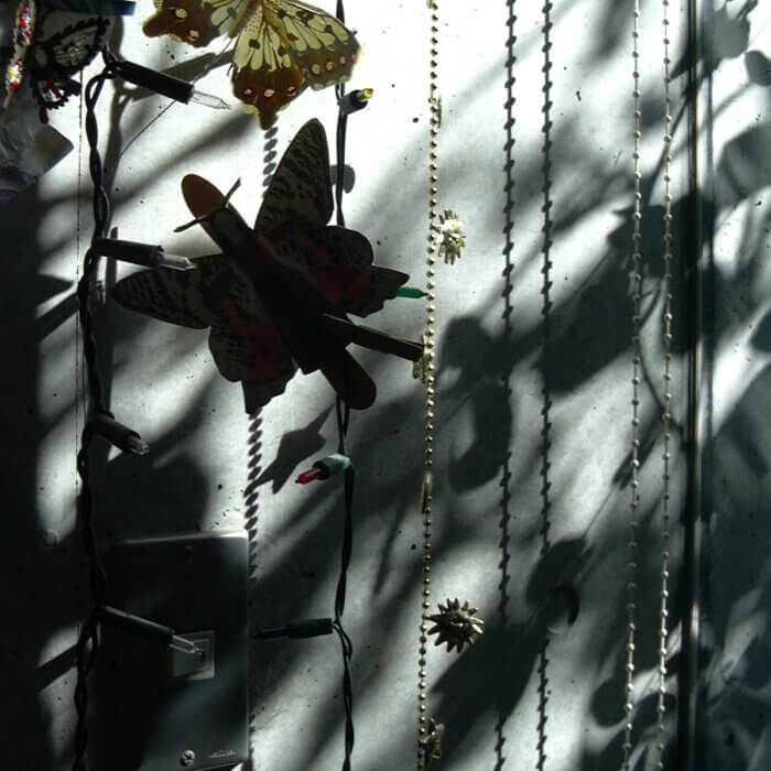 吊るされたチェーンライトと、蝶の飾り物と、コンクリートの壁に映ったそれらの影