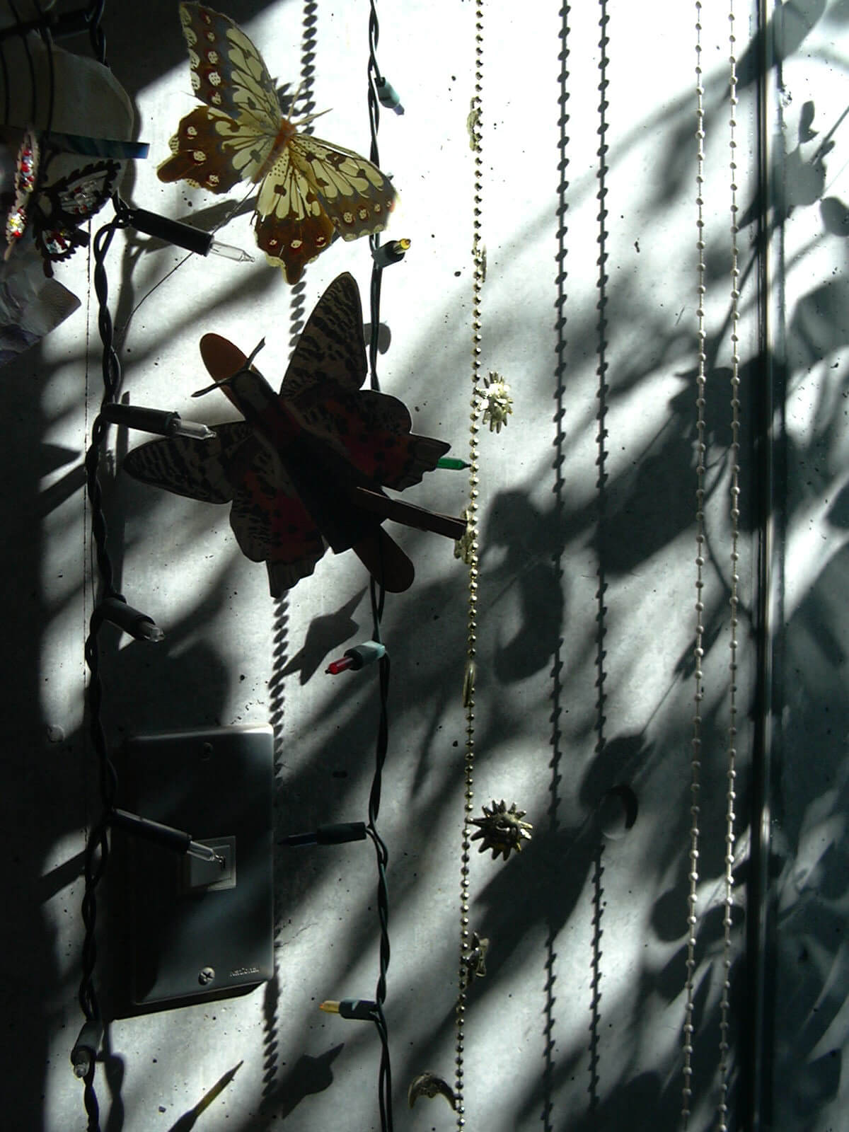 吊るされたチェーンライトと、蝶の飾り物と、コンクリートの壁に映ったそれらの影