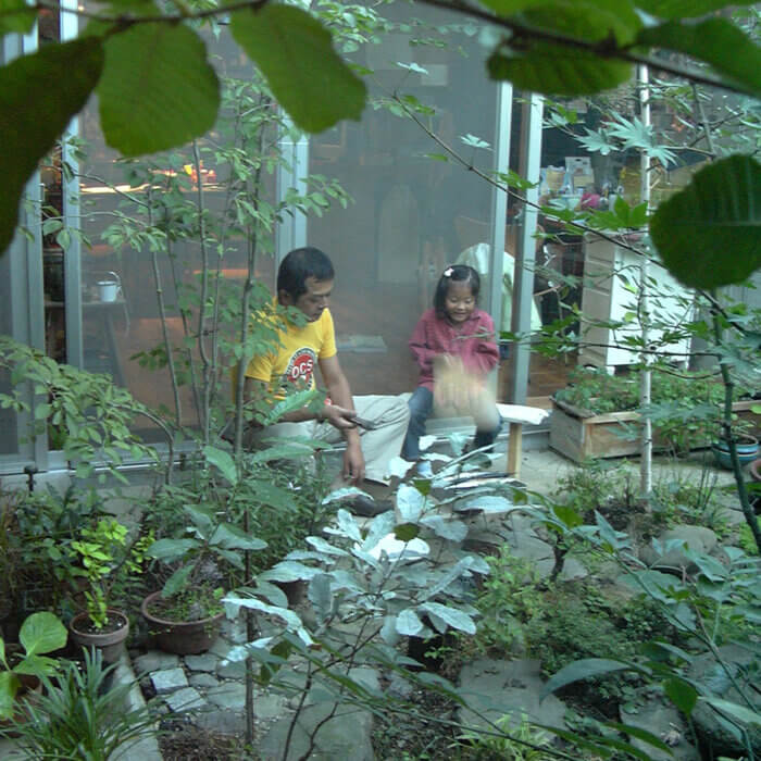 緑がたくさんある庭の縁側で座っている、父親と小学生の娘