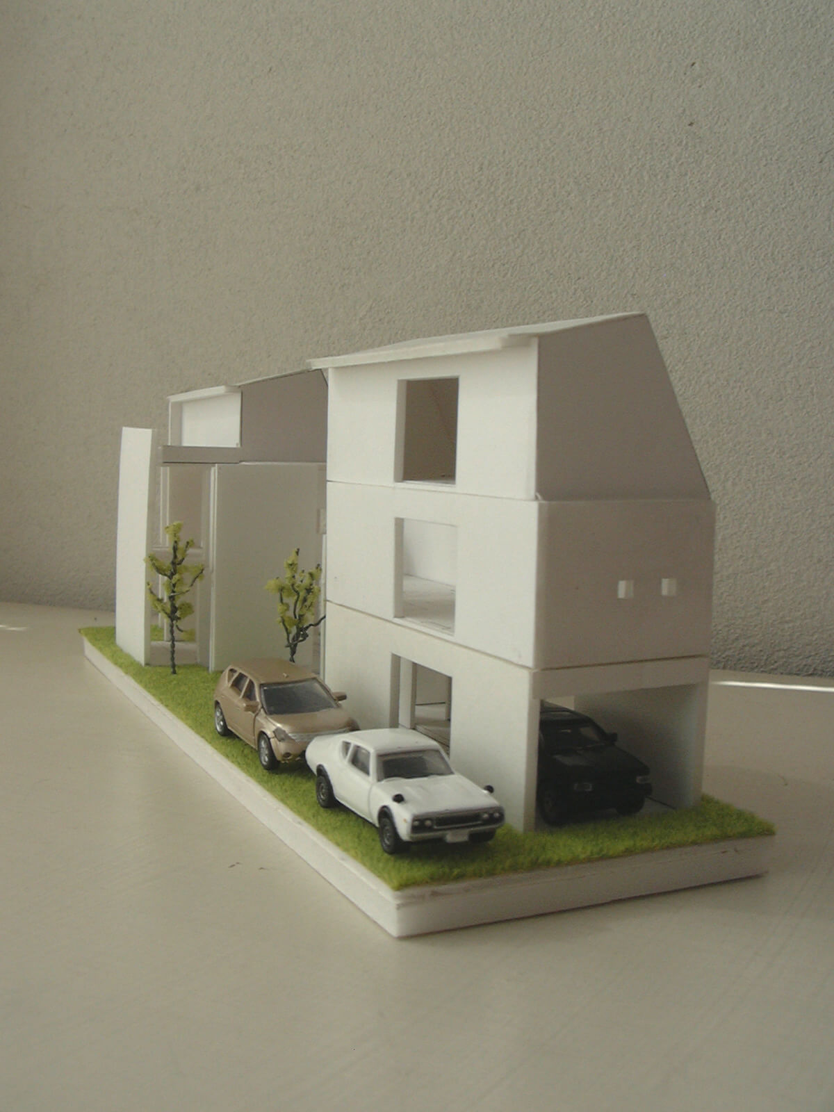 1/100の住宅模型と、その中におさめられた3台のミニカー