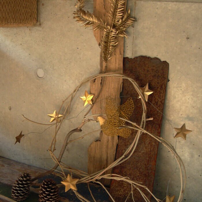 コンクリートの壁際に飾られた、木片と松ぼっくり、金色の星の簡素なクリスマスデコレーション